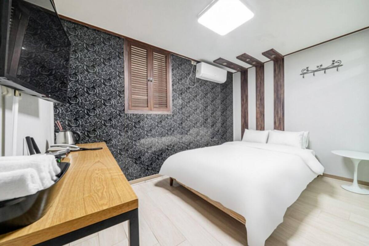 A modern bedroom with a bed, a desk, and a small table.