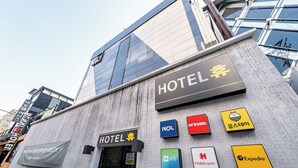 A hotel facade with multiple signage, including a prominent 'HOTEL' sign and various brand logos like NOL, Agoda, and Expedia. - Hotel Hue (Incheon)