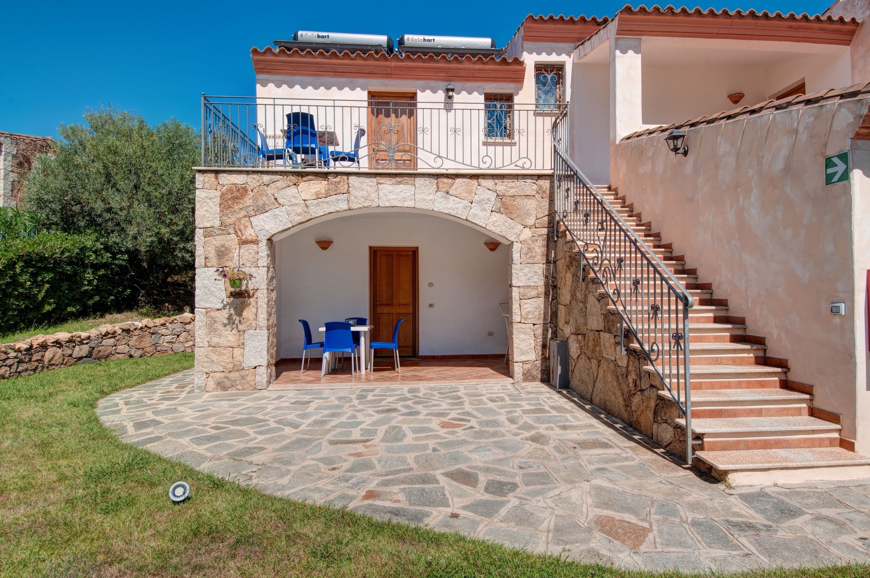 A stone patio with a table and chairs, a staircase, and a door leading to a room.