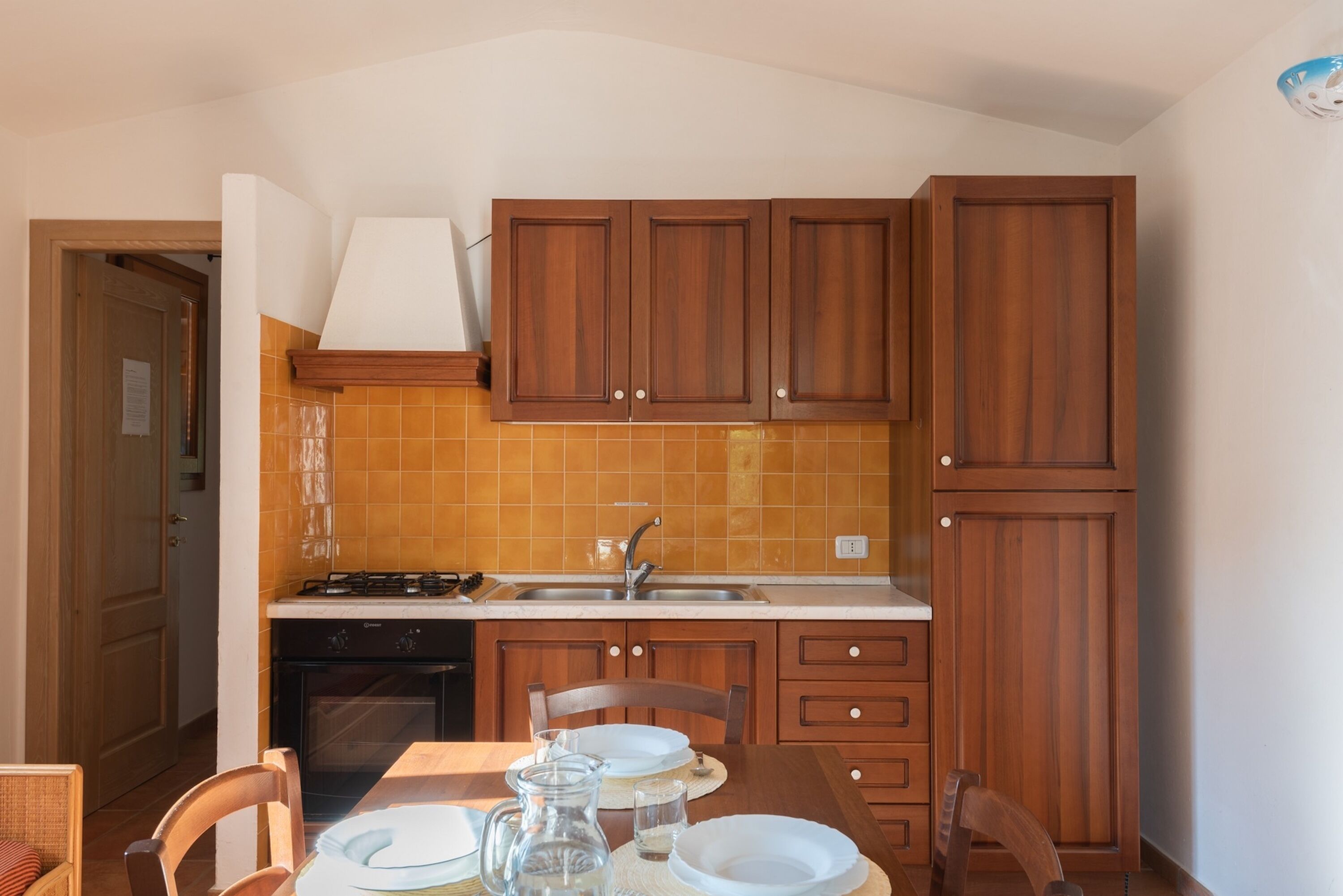 Une cuisine avec des meubles de rangement en bois, une cuisinière et un évier.