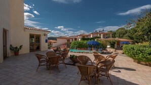 Un patio con mobiliario de mimbre y una zona de piscina.