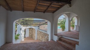 Una veranda coperta con pareti in pietra, travi in legno e vista sul paesaggio circostante.