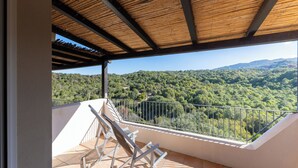 Een balkon met uitzicht op een beboste helling.
