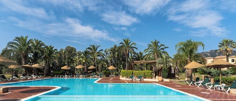 A large outdoor swimming pool with multiple lanes, surrounded by palm trees and lounge chairs.