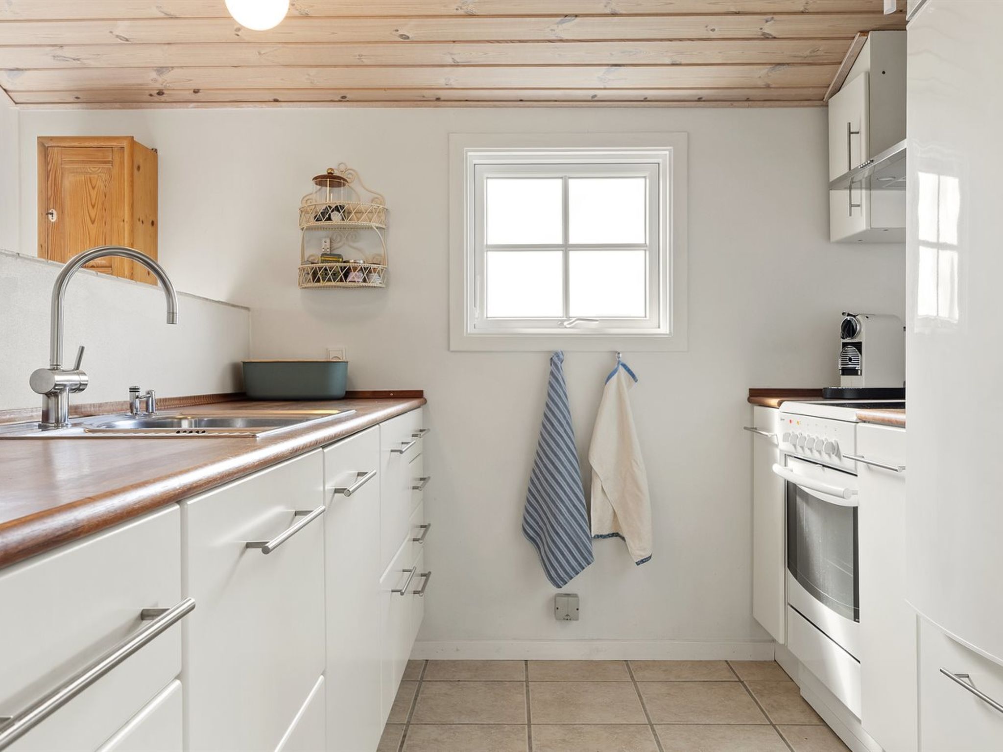 A kitchen with white cabinets, a wooden countertop, a built-in oven, and a window above the sink.