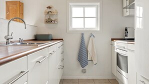 A kitchen with white cabinets, a wooden countertop, a built-in oven, and a window above the sink. - "Gjuro" - 400m from the sea by Interhome (Hjørring)