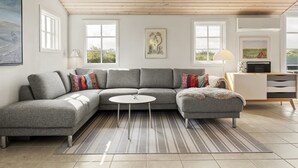 A modern living room with a grey sectional sofa, a round coffee table, and a striped rug. - "Gjuro" - 400m from the sea by Interhome (Hjørring)