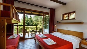 Una habitación con dos camas, cabecera de madera, ventana y balcón con mobiliario exterior.