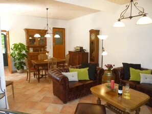 A cozy living room with a brown leather sofa, a wooden coffee table, and a dining area with a wooden table and chairs. - Moselidyll-Traumferienwohnung in exponierter Moselufer-Lage by Interhome (Traben-Trarbach)