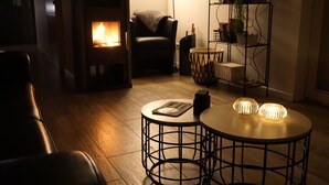 Un accogliente soggiorno con stufa a legna, divano in pelle e due tavoli rotondi con luci decorative.