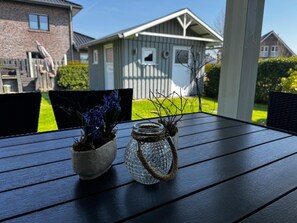 Een houten tafel met twee planten in potten en een glazen pot met touwkoord.