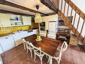 A kitchen with white cabinets, a wooden dining table, and a staircase. - GITE im Herzen der Drôme Provençale by Interhome (La Begude de Mazenc)