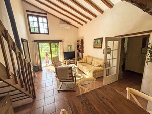 A spacious living area with a wooden ceiling, a television, a sofa, and a bookshelf. - GITE im Herzen der Drôme Provençale by Interhome (La Begude de Mazenc)