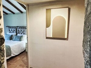 Ein Schlafzimmer mit einem Bett, einem Kopfteil und einem an der Wand befestigten Spiegel.