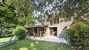 Ein Steinhaus mit Terrasse, Sitzgelegenheiten im Freien und einem Rasen.