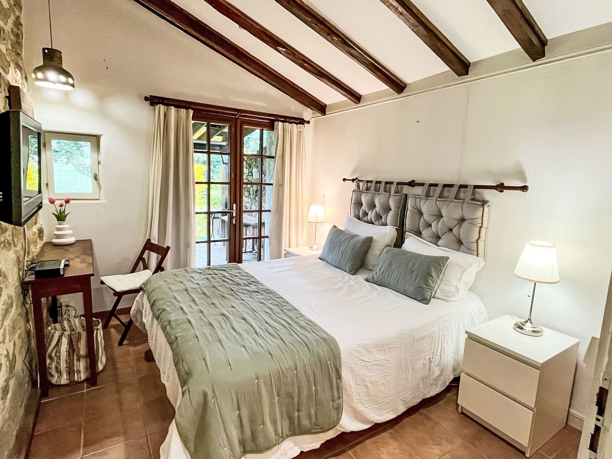 A bedroom with a bed, bedside tables, a desk, a chair, and a window with curtains.