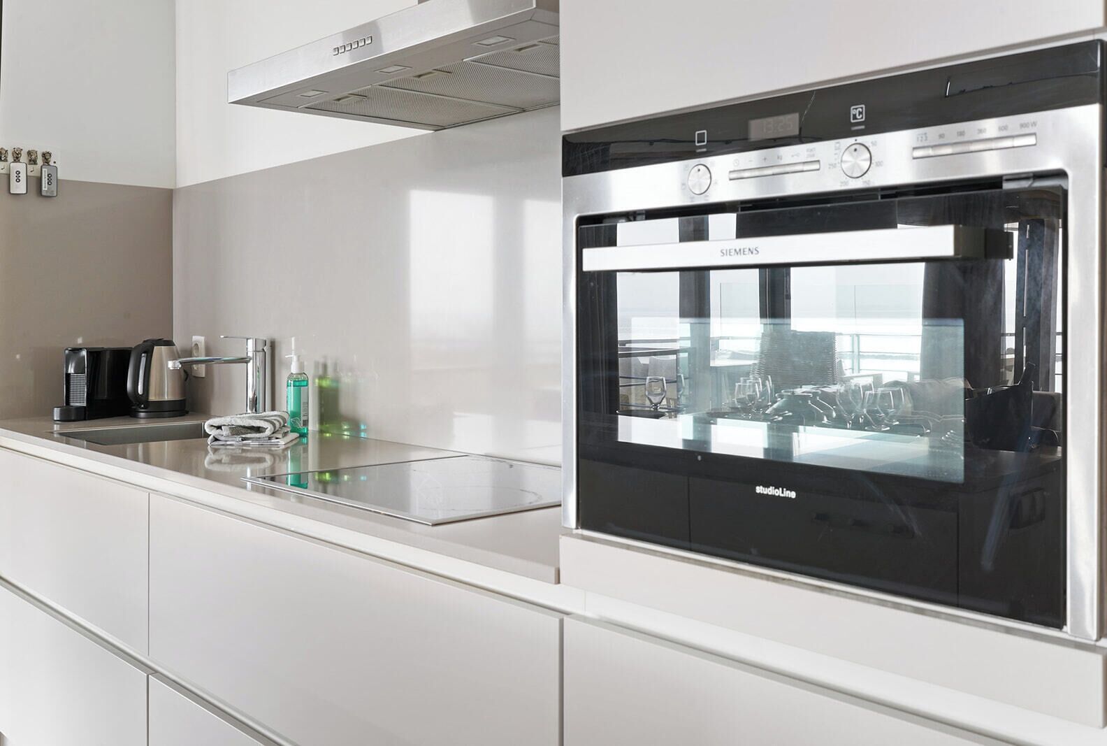 Una cocina moderna con horno empotrado, cafetera y hervidor sobre la encimera.