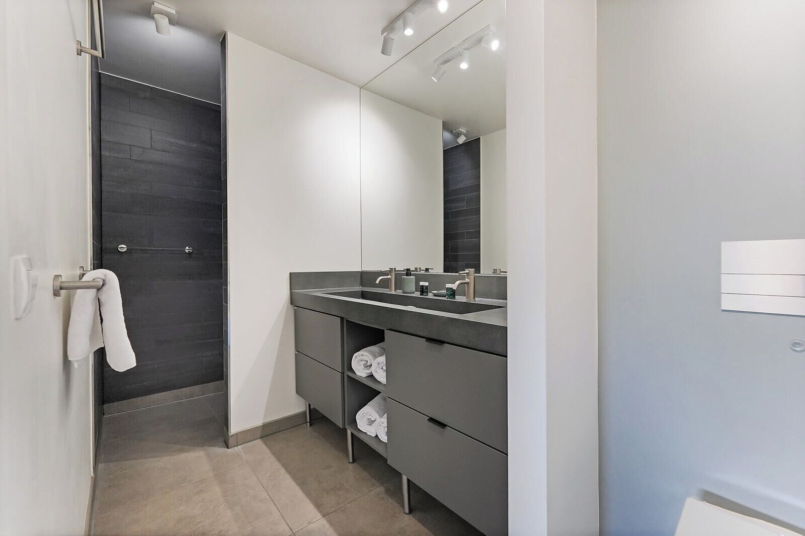 Un baño moderno con un espejo grande, un lavabo y un perchero para toallas.