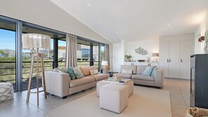 A spacious living area with a large window, a sofa set, a coffee table, and a cabinet. - The 4-person Villa Super VIP features a luxurious and comfortably furnished interior with a direct waterfront location, various terraces offering unobstructed views over the water. (Ouddorp)
