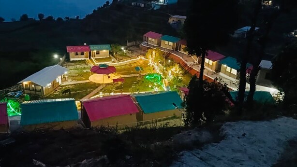A small, brightly lit village with several buildings, including a prominent structure with a red roof and a sign that reads "VANHOE JUNCTION." - Bamboo Junction Resort (Tehri)