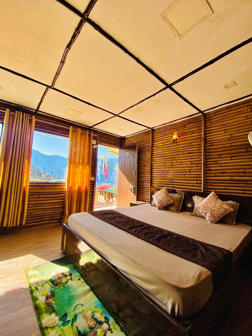 Un dormitorio con cama, paneles de madera, una ventana con cortinas y vistas al exterior.