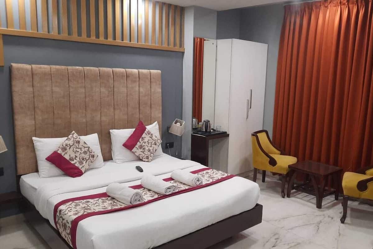 A hotel room with a bed, two chairs, a desk, and a wardrobe.