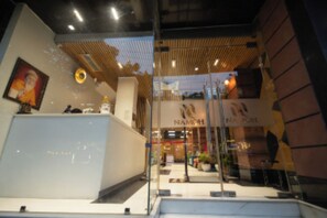 A modern interior with a reception desk, a staircase, and a sign for 'NAMOH'. - Hotel Namoh (New Delhi)