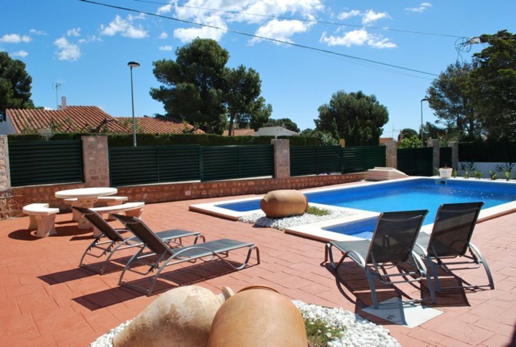 A pool area with lounge chairs, a table, and a small pool.