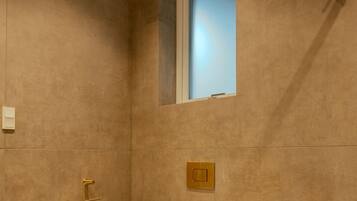 Un baño moderno con inodoro blanco, una ventana pequeña y un perchero para toallas.