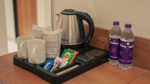 Una bandeja con una tetera, dos tazas, sobres de té, un sobre de té Lipton y dos botellas de agua Bailey's.