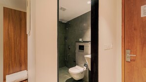 Un baño moderno con tocador de madera, inodoro y zona de ducha.