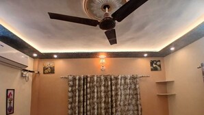 A bedroom with two beds, a ceiling fan, and a shower curtain. - Kaashvi Home Stay (Varanasi)