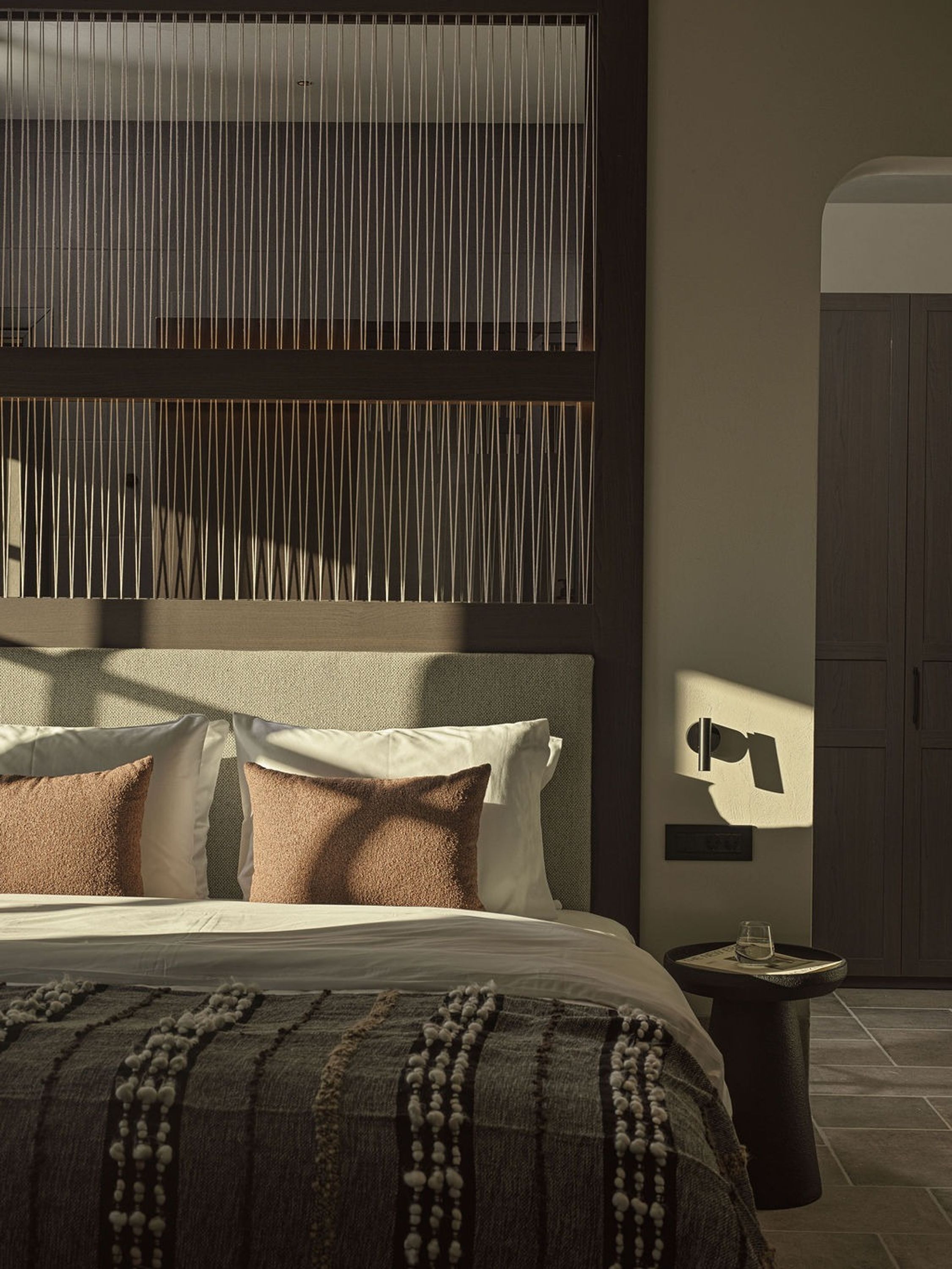 A modern bedroom with a bed, pillows, a bedside table, and a wardrobe.