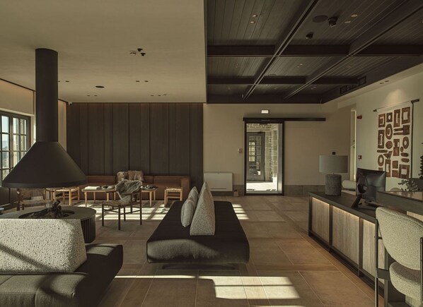 Un amplio salón con chimenea, asientos y vistas al exterior.