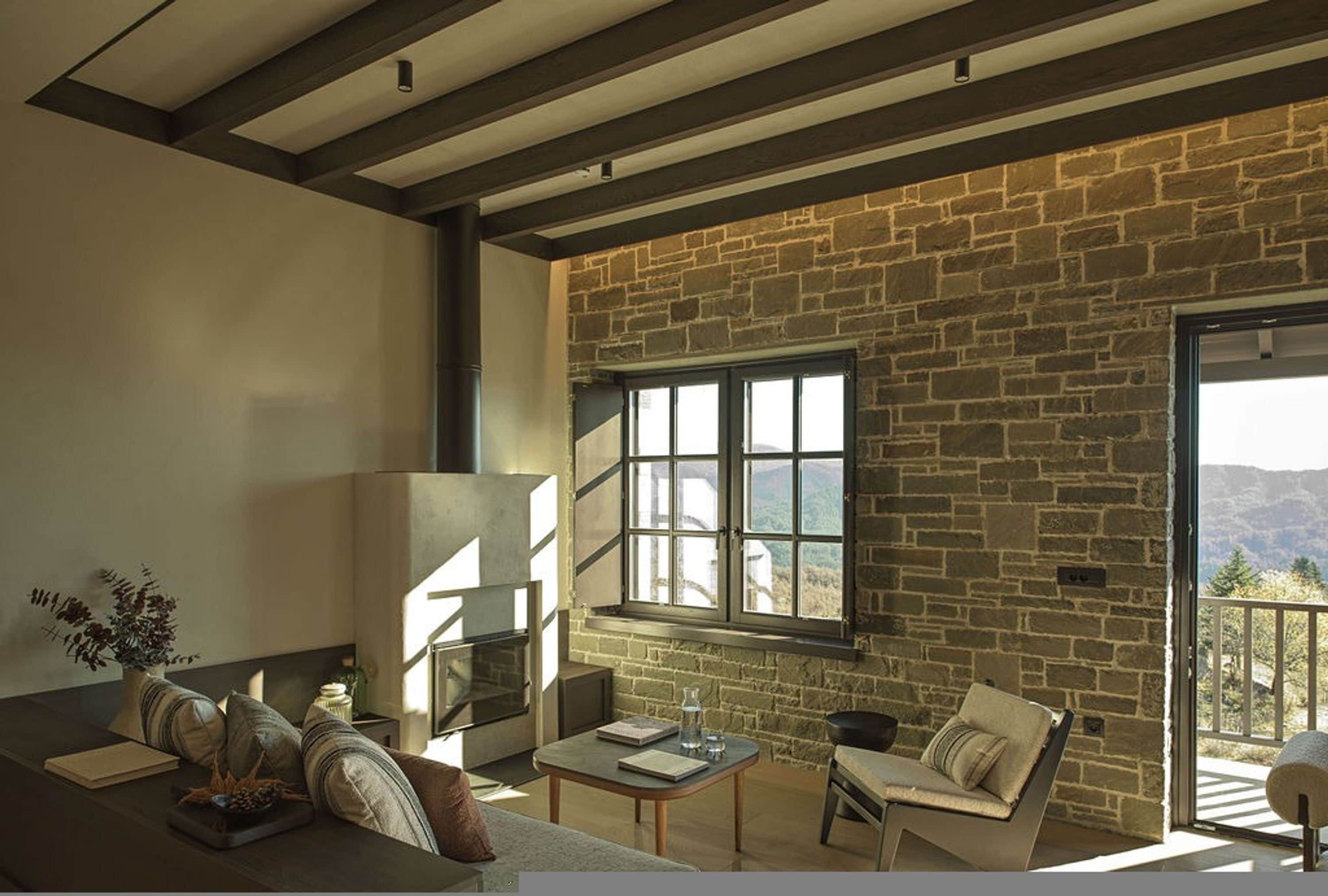 A cozy living room with a stone wall, a fireplace, a sofa, and a table.