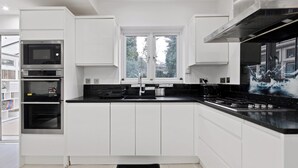 Una cucina moderna con mobili bianchi, un piano di lavoro nero e una finestra sopra il lavello.