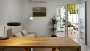 Un salon moderne avec une table à manger en bois, un canapé, une lampe sur pied et une plante en pot.