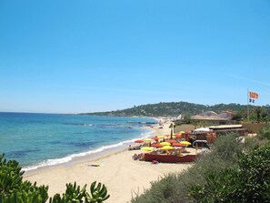 A beach with umbrellas, a boat, and a flag. - Les Coteaux de la Nartelle by Interhome (Sainte Maxime)