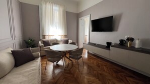 A modern living room with a sofa, a round dining table, and a flat-screen TV mounted on the wall. - Turin Central Cavour (Turin)