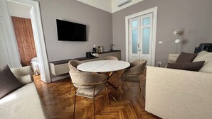 A modern living room with a round table, two sofas, a flat-screen TV, and a kitchen area with a coffee machine. - Turin Central Cavour (Turin)