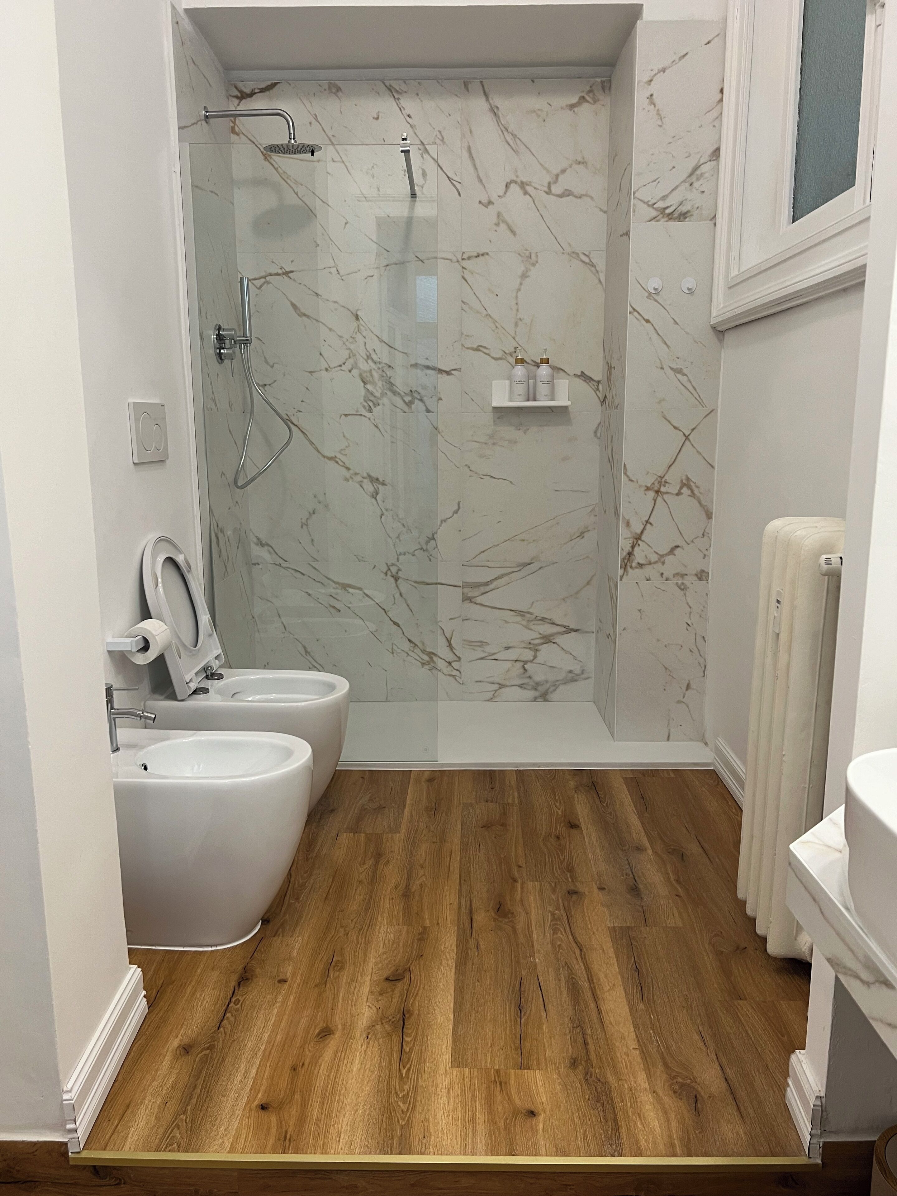 Un bagno moderno con doccia, due bidet, un water e un lavabo.
