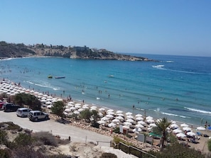 A beach with numerous umbrellas, a rocky coastline, and a clear view of the sea. - Villa Nayia Paradise with stunning views by Interhome (Tsadha)