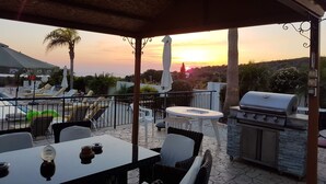 Un patio con mesa, sillas, una parrilla y sillones.