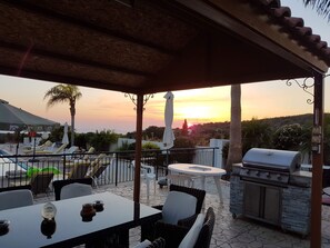 Eine Terrasse mit Tisch, Stühlen, Grill und Liegestühlen.