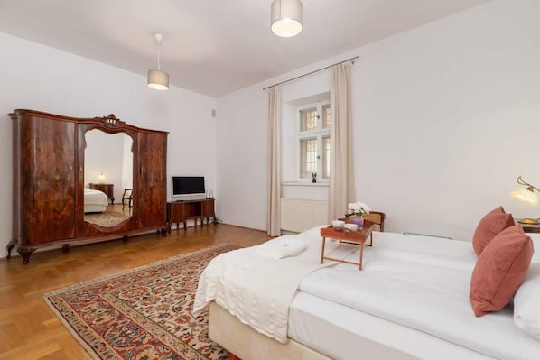 A bedroom with a large bed, a wooden wardrobe, a television, and a window with curtains. - Spacious Apartment on the Market | Balcony | Old Town (Kraków)