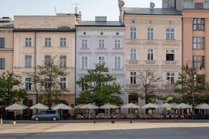 A row of European-style buildings with outdoor seating areas and a parked car. - Spacious Apartment on the Market | Balcony | Old Town (Kraków)