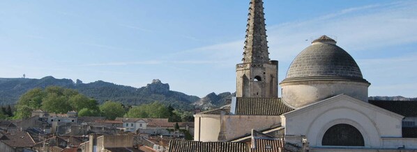 A historic building with a prominent tower and dome, surrounded by a cityscape and hills. - OUSTAU DE MARIE (St.-Remy-de-Provence)