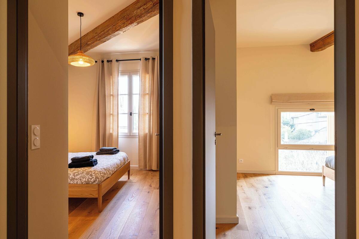Ein Schlafzimmer mit einem hölzernen Bett, einer Pendelleuchte und einem Fenster mit Vorhängen.