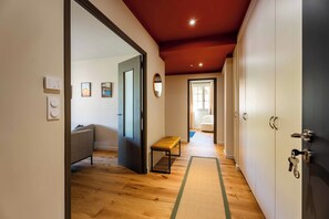 A hallway with wooden flooring, a bench, a sofa, and a door leading to another room. - OUSTAU DE MARIE (St.-Remy-de-Provence)
