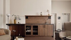Une cuisine moderne avec des meubles en bois, un plan de travail en marbre et un évier encastré. On y trouve un canapé et une petite table sur laquelle sont posés un livre et une bougie.